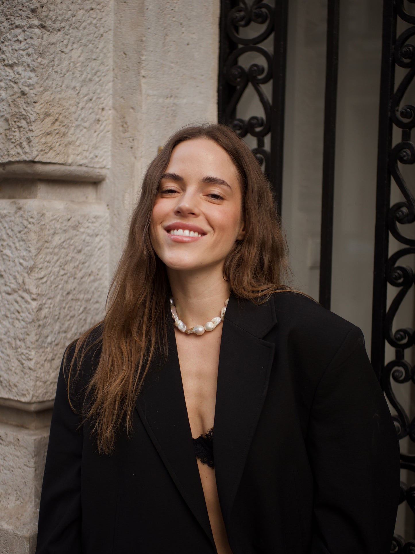Woman wears bold Keshi pearl necklace and a suit