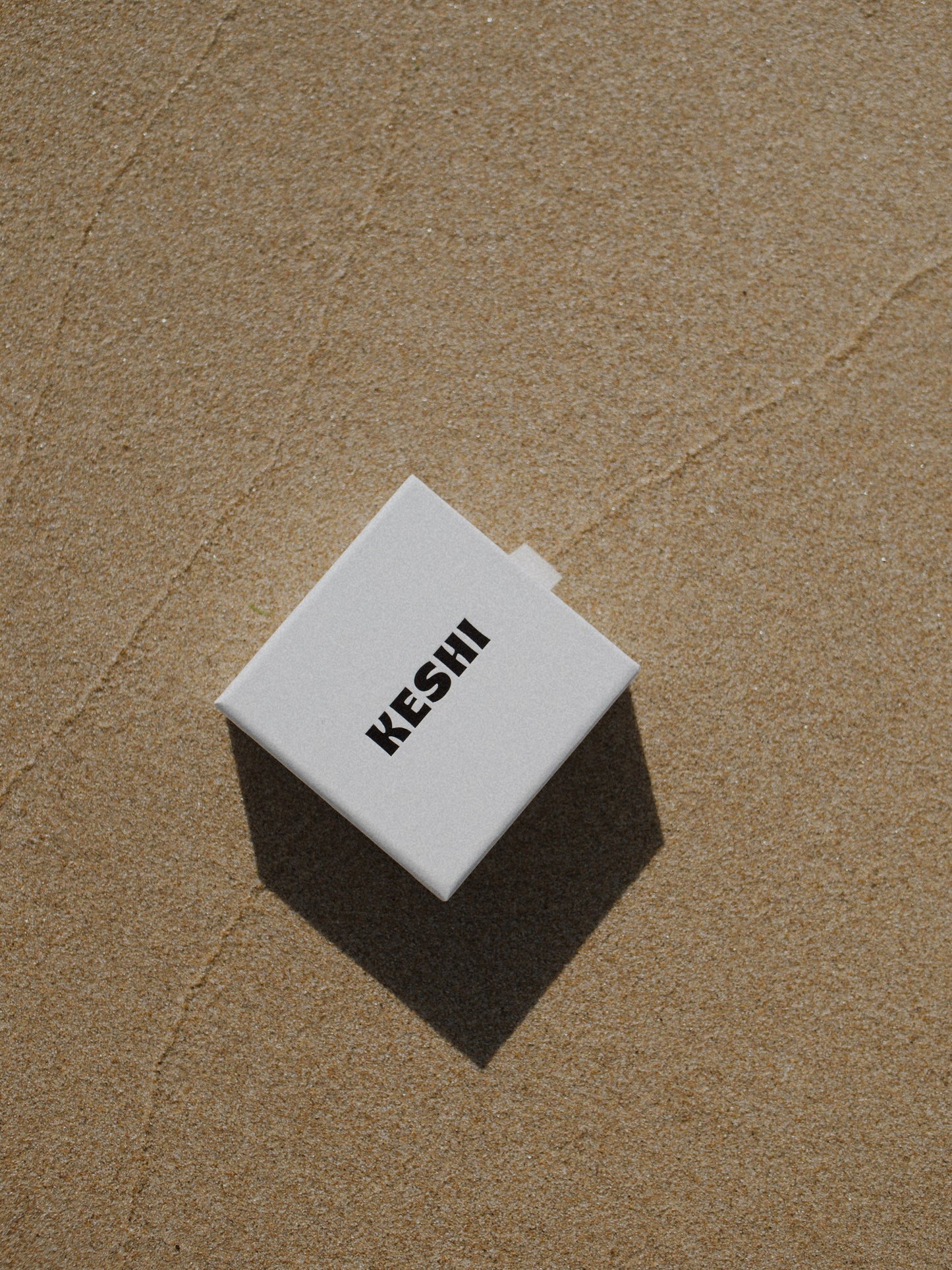 White cube with 'KESHI' text on a textured brown surface
