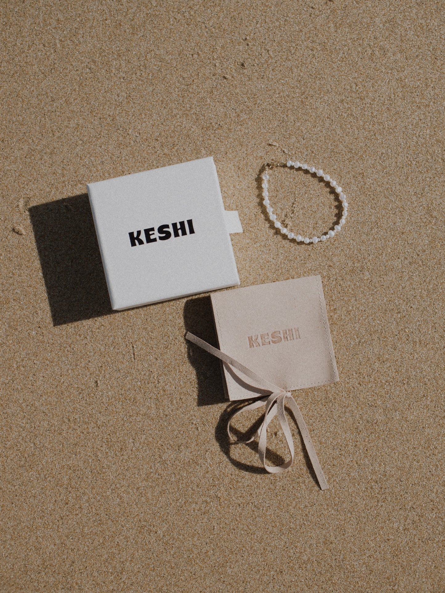 Pearl bracelet and branded Keshi packaging on sand