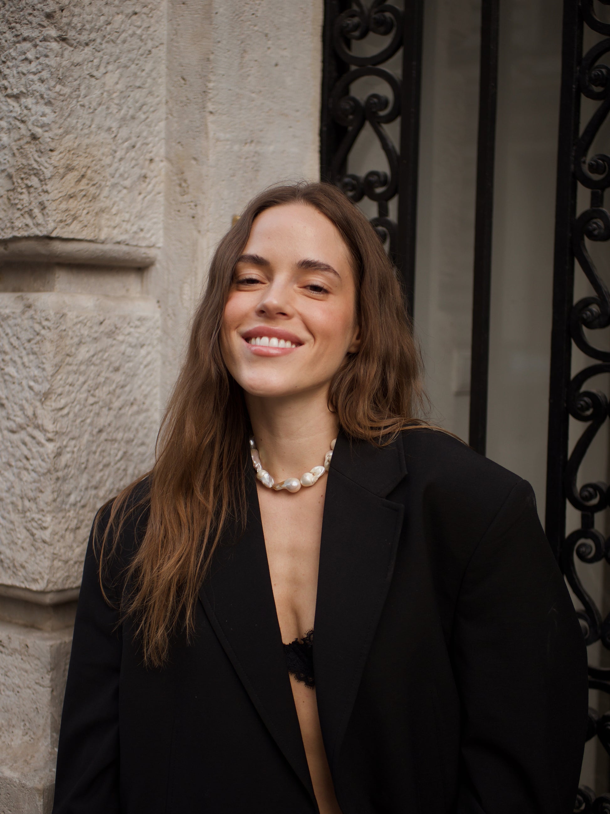 Woman wears bold Keshi pearl necklace and a suit 