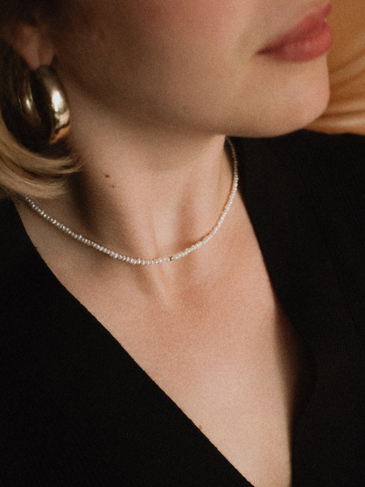 Close-up of a person wearing a delicate Keshi choker necklace with a blurred background