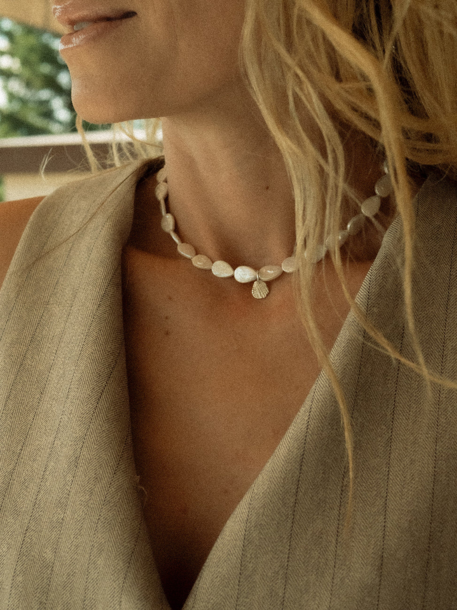 Keshi necklace made out of drop shaped pearls, worn by a blond girl with silver seashell pendant. 